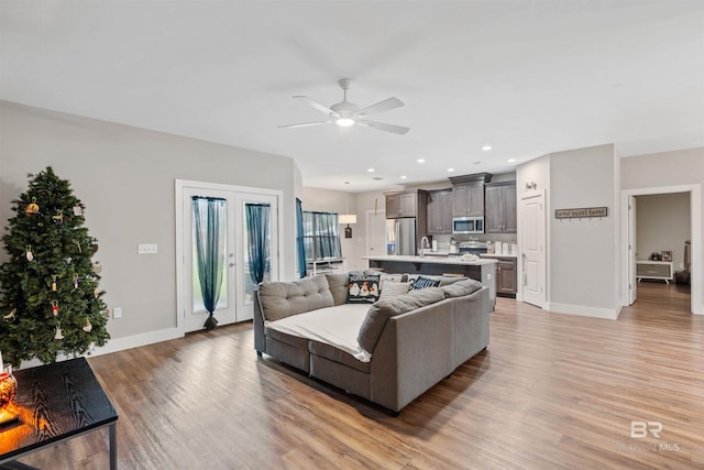 living room featuring sink, ceiling fan, french doors, and light hardwood / wood-style floors