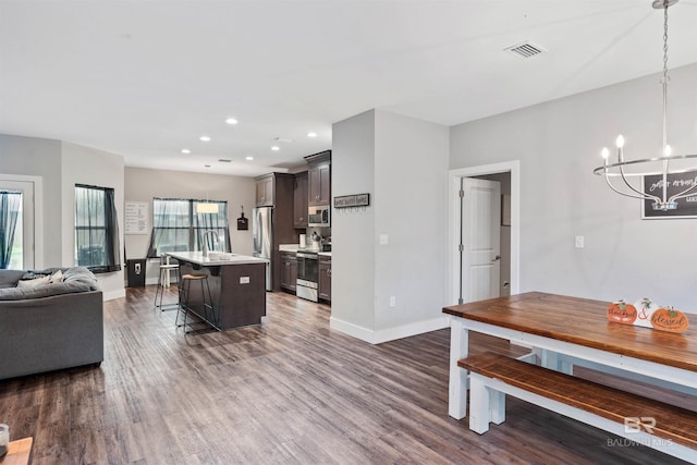 kitchen with hanging light fixtures, dark hardwood / wood-style floors, a center island, and a breakfast bar