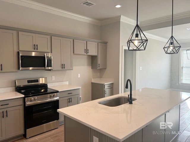 kitchen featuring pendant lighting, sink, appliances with stainless steel finishes, light stone counters, and an island with sink