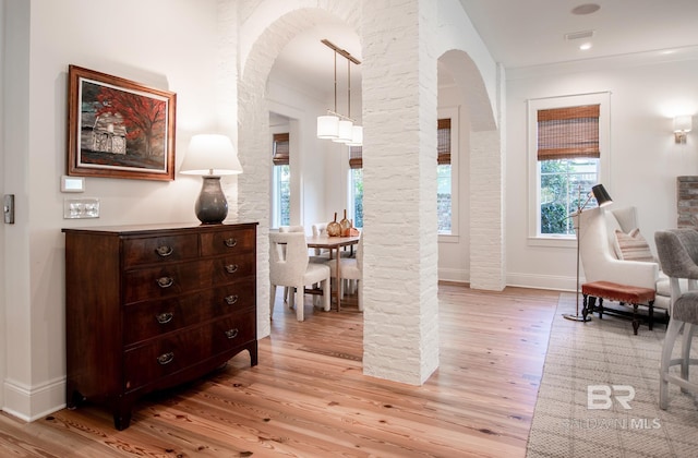 interior space with decorative columns, ornamental molding, and light hardwood / wood-style flooring