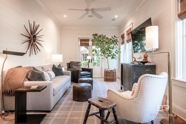 living area featuring ceiling fan and wood walls