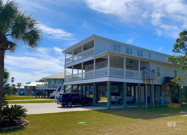 exterior space featuring a yard, concrete driveway, stairway, ceiling fan, and a carport