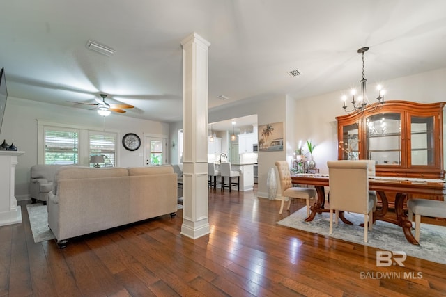 dining room with visible vents, dark wood-type flooring, ceiling fan with notable chandelier, decorative columns, and baseboards