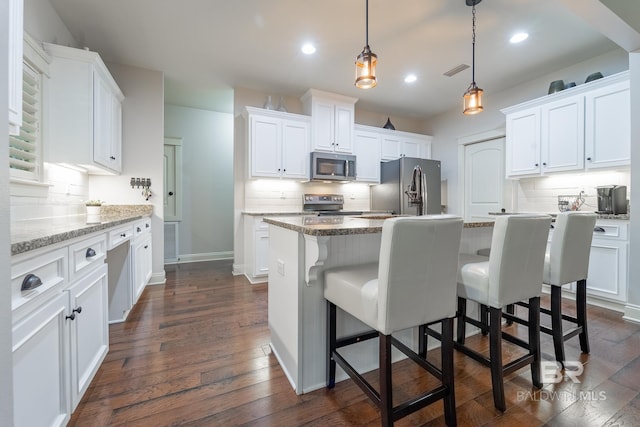 kitchen with stone countertops, white cabinetry, dark hardwood / wood-style flooring, a center island, and appliances with stainless steel finishes