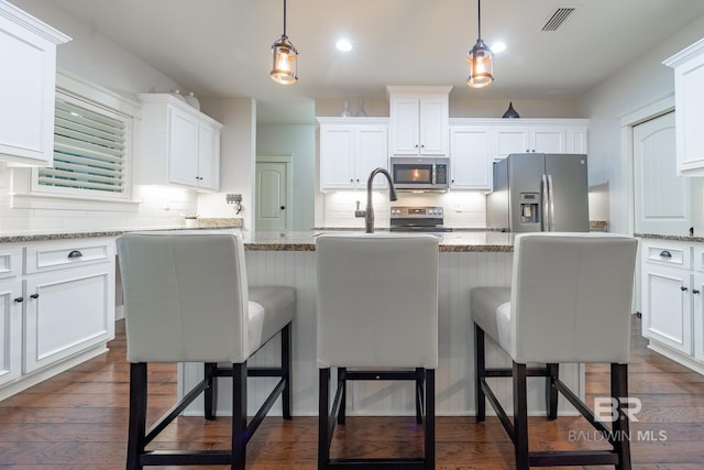 kitchen with visible vents, dark wood finished floors, hanging light fixtures, white cabinets, and appliances with stainless steel finishes