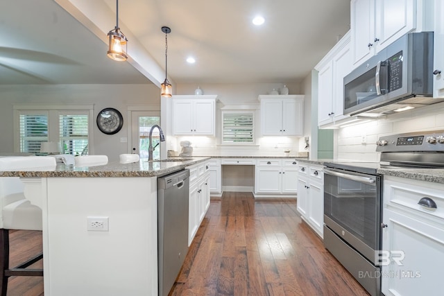 kitchen featuring a breakfast bar, a sink, backsplash, appliances with stainless steel finishes, and white cabinets