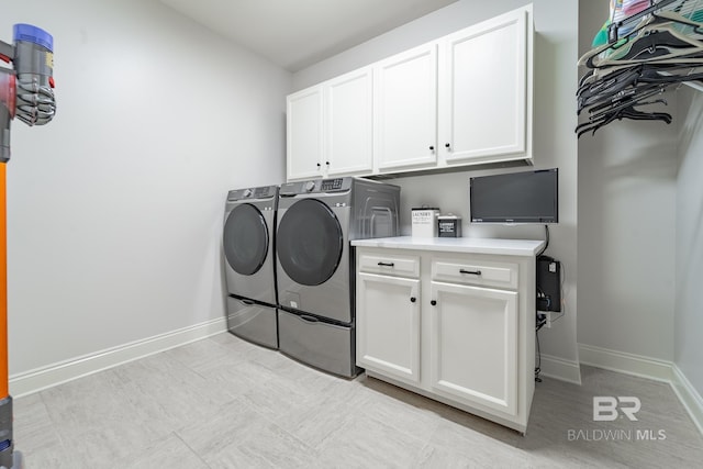 clothes washing area featuring cabinets and washer and clothes dryer