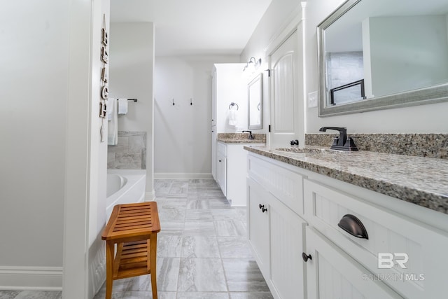 full bath with a bath, two vanities, baseboards, and a sink