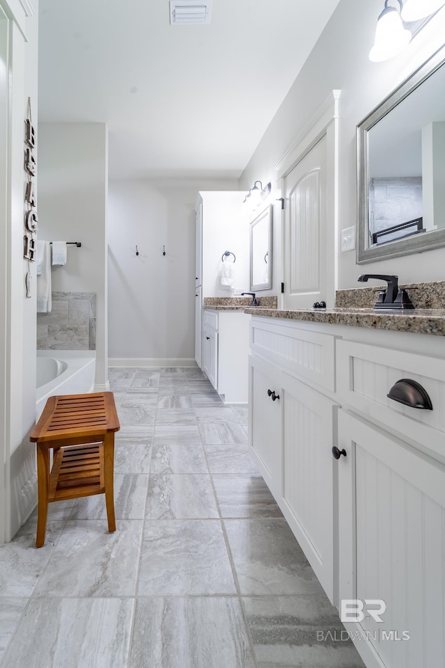 full bathroom featuring a bath, visible vents, vanity, and baseboards