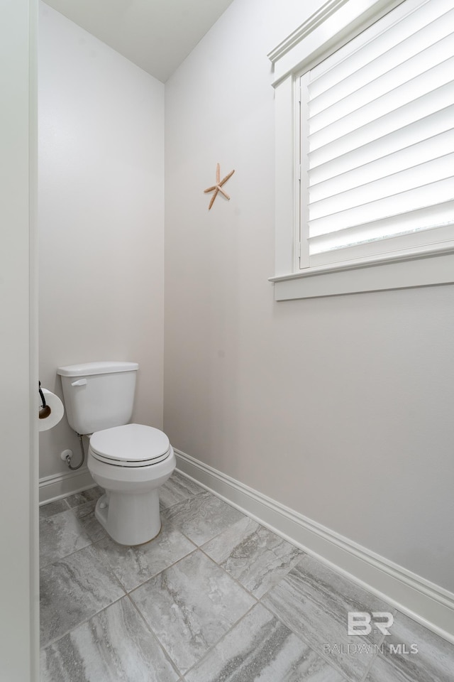 bathroom featuring toilet, baseboards, and marble finish floor