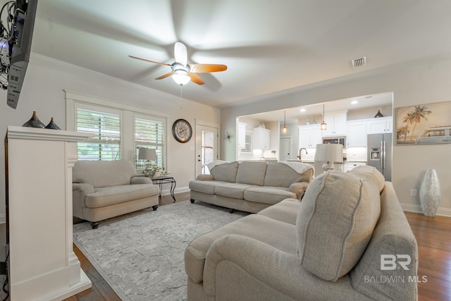 living area with ceiling fan, visible vents, baseboards, and wood finished floors