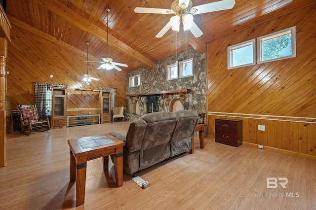 living room featuring light hardwood / wood-style flooring, beam ceiling, a stone fireplace, wooden ceiling, and wood walls