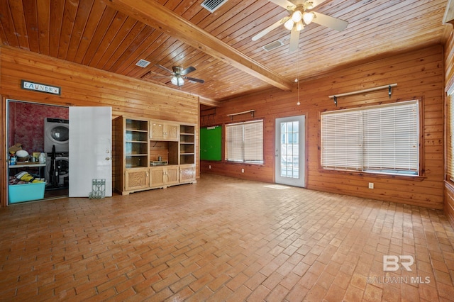 unfurnished living room with wood ceiling, wooden walls, and stacked washer / dryer