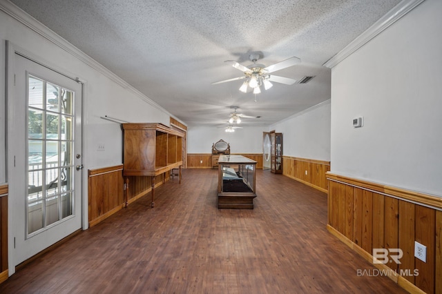 interior space featuring wood walls, ornamental molding, ceiling fan, dark wood-type flooring, and a textured ceiling