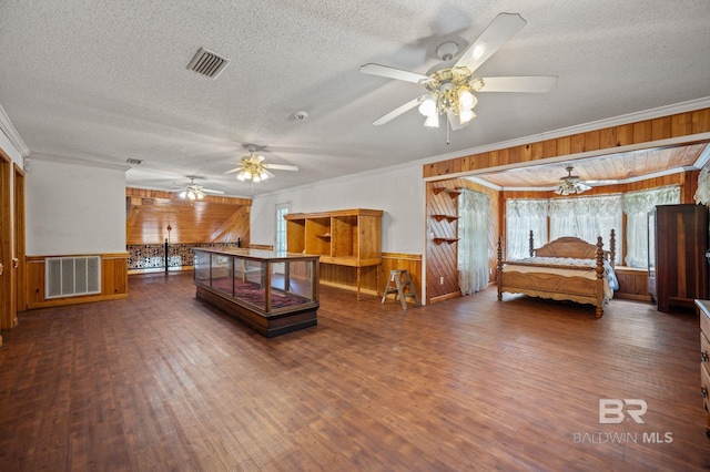 bedroom with crown molding, dark wood-type flooring, a textured ceiling, and wood walls