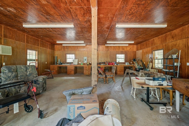 misc room featuring wood ceiling, a wall mounted AC, concrete floors, wooden walls, and a workshop area