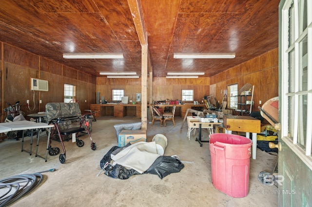 miscellaneous room with a workshop area, concrete flooring, a wealth of natural light, and wood walls