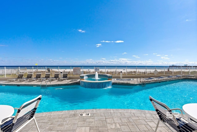 view of swimming pool featuring pool water feature, a hot tub, and a water view