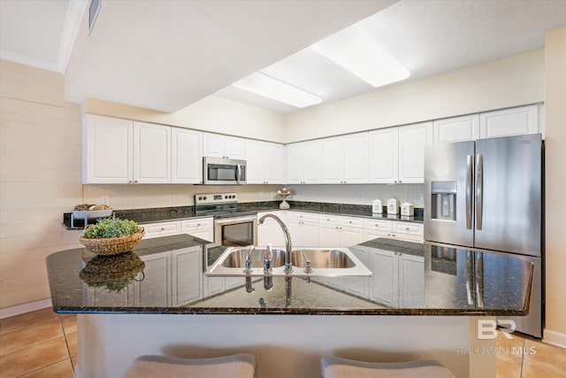 kitchen with a kitchen bar, appliances with stainless steel finishes, sink, and white cabinetry