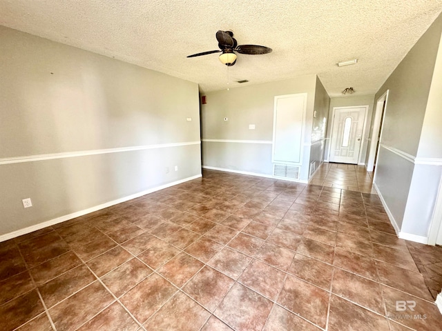 tiled spare room with a textured ceiling and ceiling fan