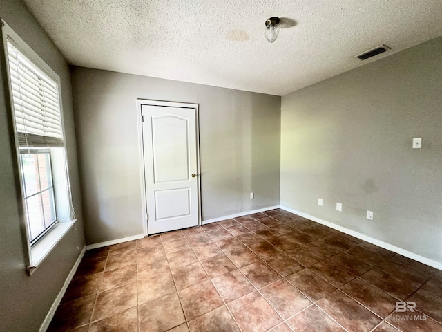 empty room featuring a wealth of natural light and a textured ceiling