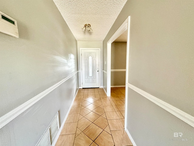 doorway to outside with light tile patterned flooring and a textured ceiling