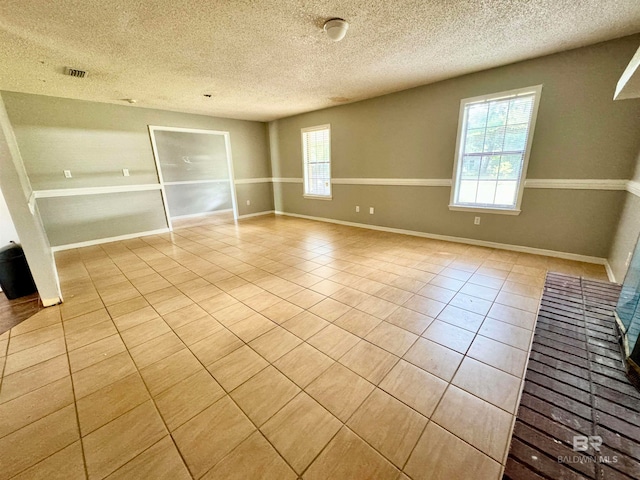 unfurnished room featuring light tile patterned flooring and a textured ceiling