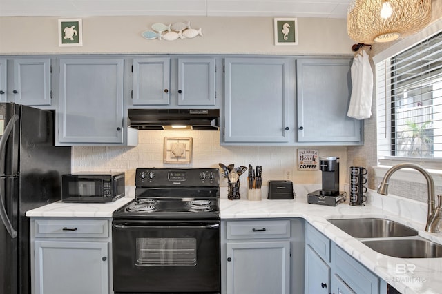 930 W Beach Blvd Unit 106, Gulf Shores, AL 36542 - kitchen featuring black appliances, under cabinet range hood, a sink, tasteful backsplash, and light stone countertops