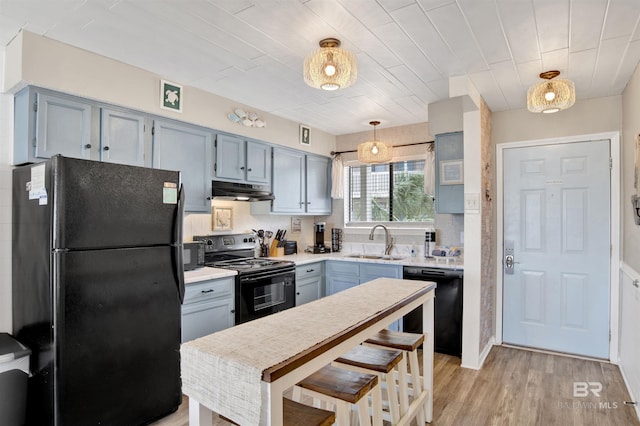 930 W Beach Blvd Unit 106, Gulf Shores, AL 36542 - kitchen featuring black appliances, a sink, under cabinet range hood, light countertops, and light wood finished floors