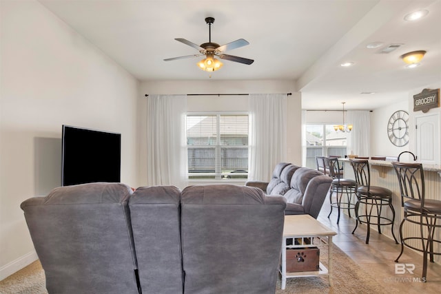 living room with visible vents, ceiling fan with notable chandelier, and baseboards