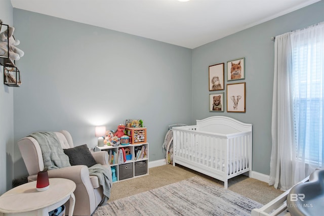 bedroom featuring a crib, carpet, and baseboards