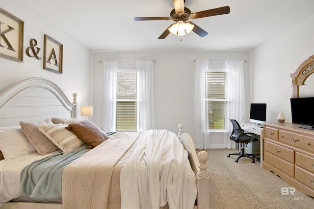 bedroom featuring light carpet, multiple windows, baseboards, and a ceiling fan