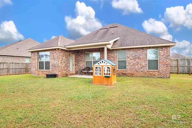 rear view of property with a patio, a yard, a fenced backyard, and brick siding