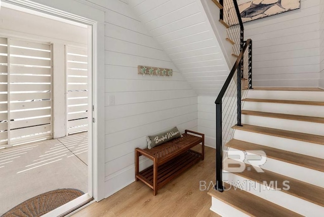 staircase with wood walls and wood finished floors