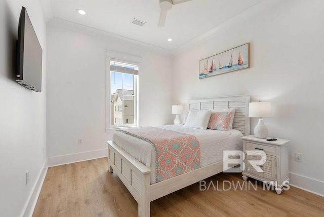 bedroom featuring light wood finished floors, visible vents, baseboards, ceiling fan, and ornamental molding