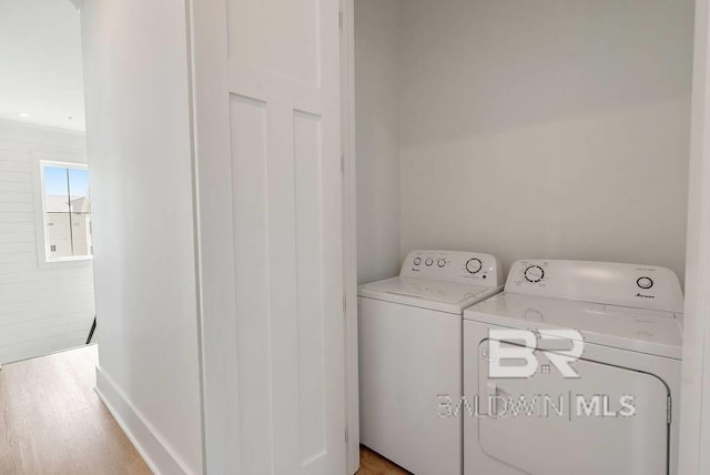 laundry area with laundry area, washer and clothes dryer, and wood finished floors