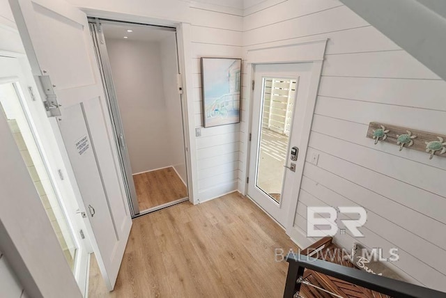 doorway featuring wood walls and light wood-style flooring