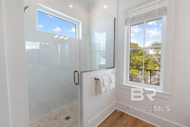 full bathroom featuring a stall shower, baseboards, and wood finished floors