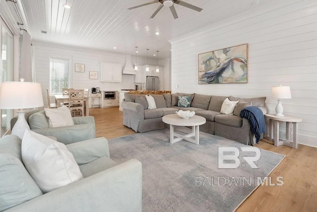 living area with ceiling fan, recessed lighting, light wood-type flooring, and wood ceiling