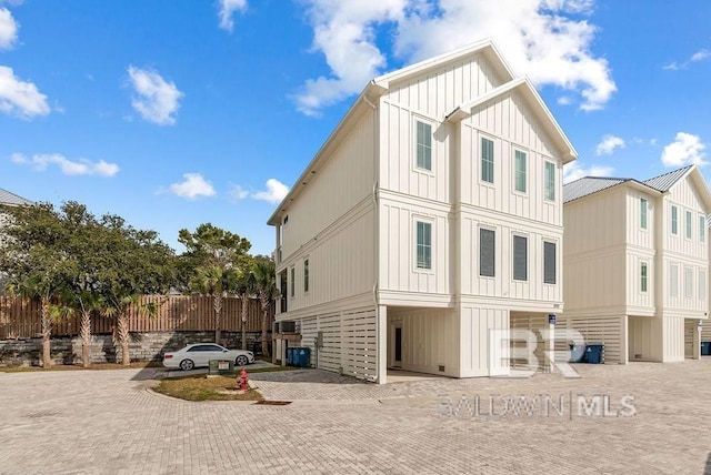 rear view of property featuring board and batten siding and decorative driveway