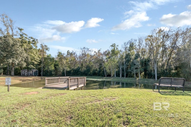 surrounding community with a lawn and a deck with water view