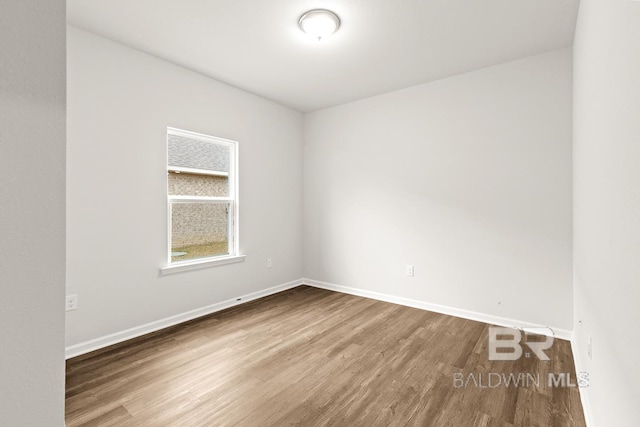 spare room with baseboards and wood finished floors