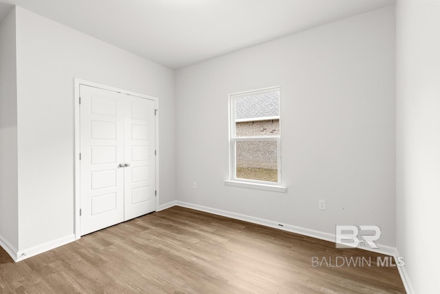 unfurnished bedroom featuring a closet, baseboards, and wood finished floors