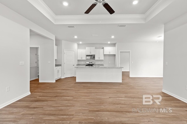 kitchen with stainless steel appliances, a raised ceiling, visible vents, light wood-style floors, and white cabinets