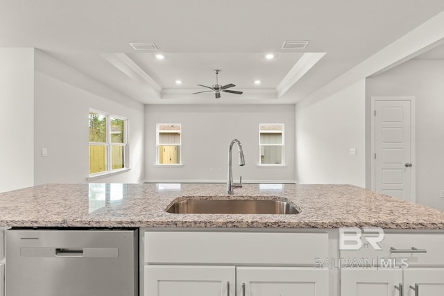 kitchen with dishwasher, a tray ceiling, a sink, and light stone countertops