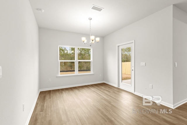 empty room featuring an inviting chandelier, baseboards, visible vents, and wood finished floors