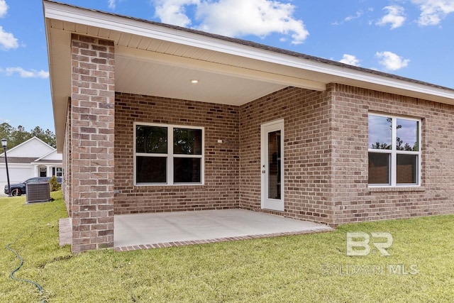 exterior space with a patio area, a lawn, and brick siding