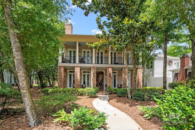 view of front of home featuring brick siding, ceiling fan, a porch, french doors, and a balcony