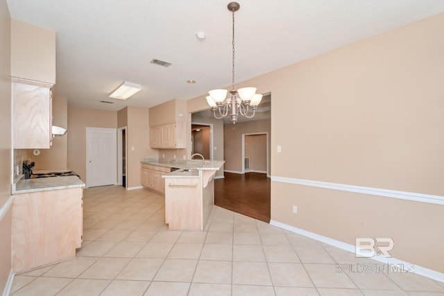 kitchen with a peninsula, light tile patterned flooring, a breakfast bar area, light countertops, and a notable chandelier