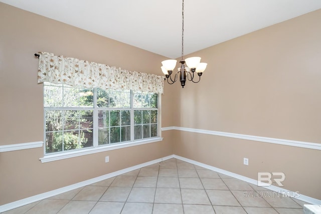 unfurnished room with baseboards, an inviting chandelier, and light tile patterned flooring